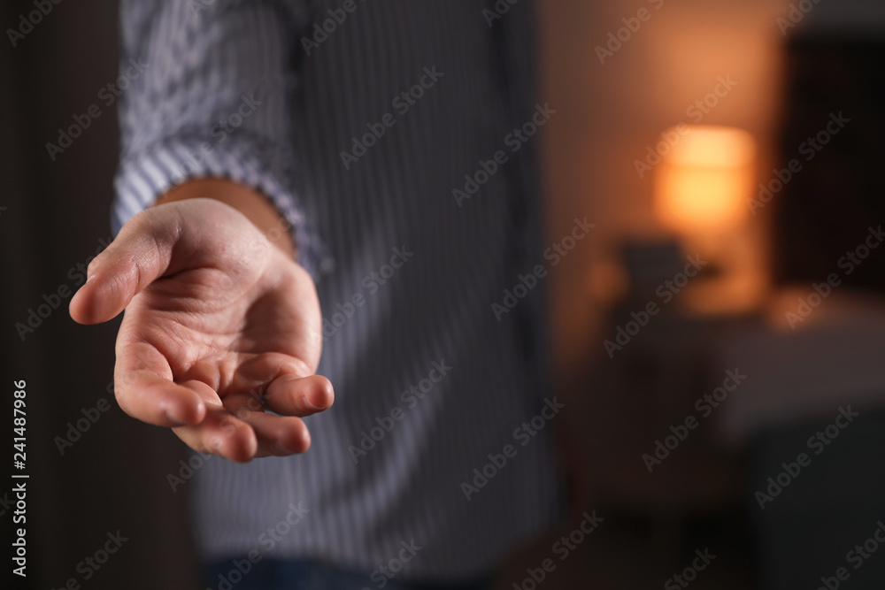 Fototapeta premium Man offering helping hand on blurred background, closeup. Space for text