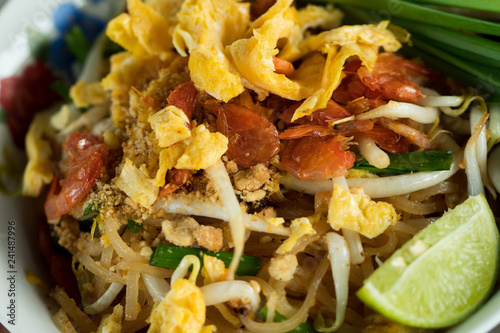 Famous fried Thai Noodle or Phad Thai in bulk big pan and plate for sale as street food by road vendor, selective focus photo