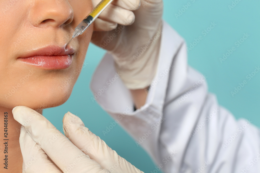 Young woman getting lips injection on color background, closeup. Cosmetic surgery Young woman getting lips injection on color background, closeup. Cosmetic surgery
