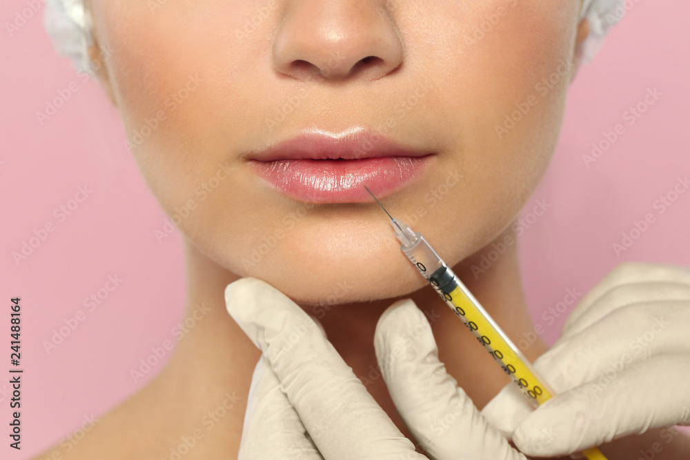Young woman getting lips injection on color background, closeup. Cosmetic surgery Young woman getting lips injection on color background, closeup. Cosmetic surgery