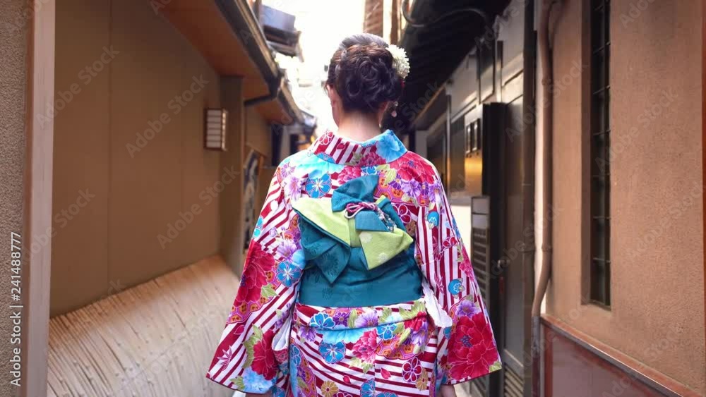 fast forward of young japanese girl in kimono dressing walking in the path to festival. back view lady in colorful beautiful traditional costume going pass by the house wooden door in hanamikoji dori fast forward of young japanese girl in kimono dressing walking in the path to festival. back view lady in colorful beautiful traditional costume going pass by the house wooden door in hanamikoji dori