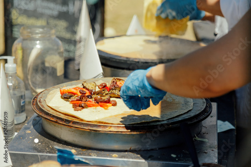 Obraz na plátně Woman puts ingredients in a pancake while cooking