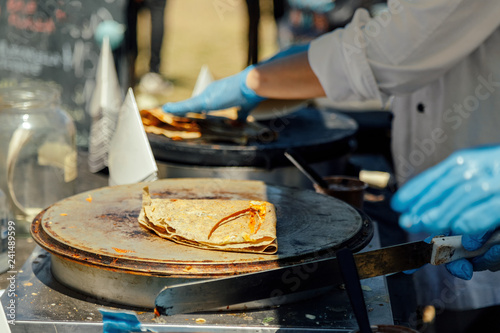 Photos Crepe folded on a hot plate while another is cooked in the background