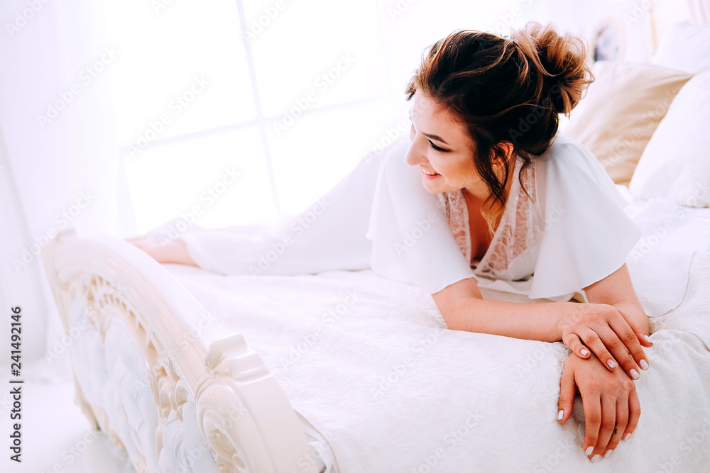Sensual brunette in silk white robe waiting on the bed Sensual brunette in silk white robe waiting on the bed
