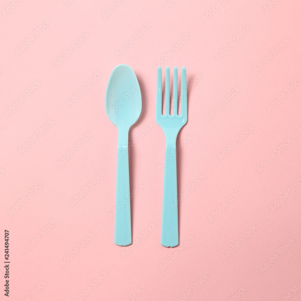 Blue plastic fork and spoon isolated on pink background Blue plastic fork and spoon isolated on pink background