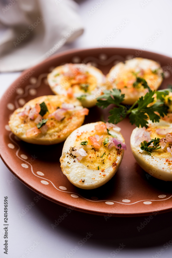 Fried hot boiled egg masala is a popular healthy breakfast or starter menu from India. With onion, coriander, black pepper, tomato and salt sprinkled over half of eggs Fried hot boiled egg masala is a popular healthy breakfast or starter menu from India. With onion, coriander, black pepper, tomato and salt sprinkled over half of eggs