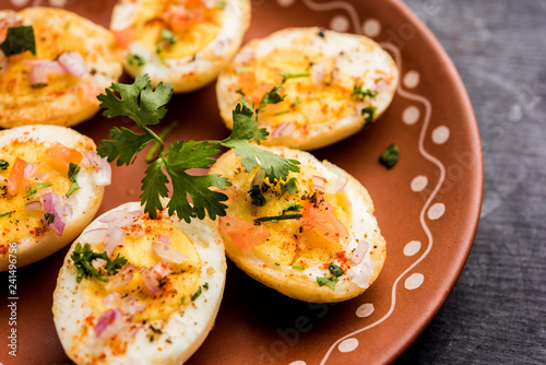 Fried hot boiled egg masala is a popular healthy breakfast or starter menu from India. With onion, coriander, black pepper, tomato and salt sprinkled over half of eggs