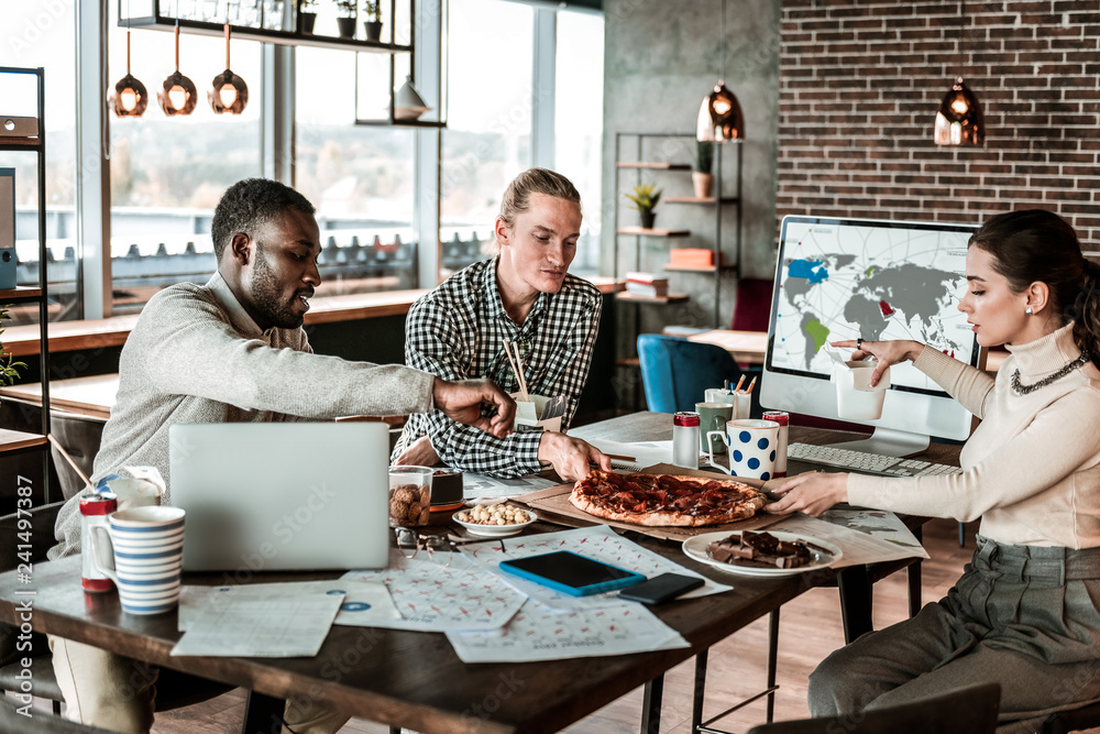 Positive delighted young people having dinner at work