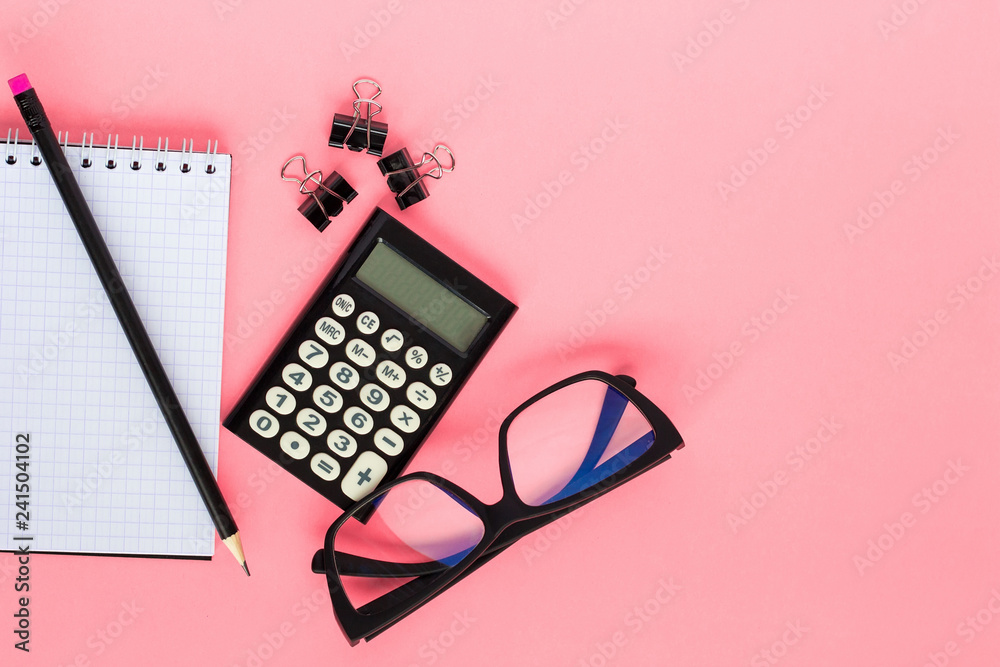 Notepad, calculator, pencil and glasses on pink background. Top view, flat lay Notepad, calculator, pencil and glasses on pink background. Top view, flat lay