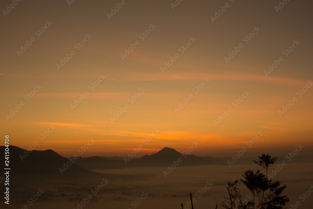 Beautiful sky sunrise. Mountain layer in morning sun ray and winter fog.