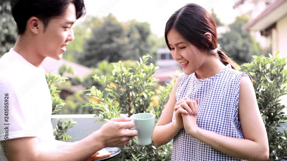 Young asian woman relaxing in the morning where her boyfriend bring her some breakfast on roof top garden. Romantic holiday concept. Young asian woman relaxing in the morning where her boyfriend bring her some breakfast on roof top garden. Romantic holiday concept.