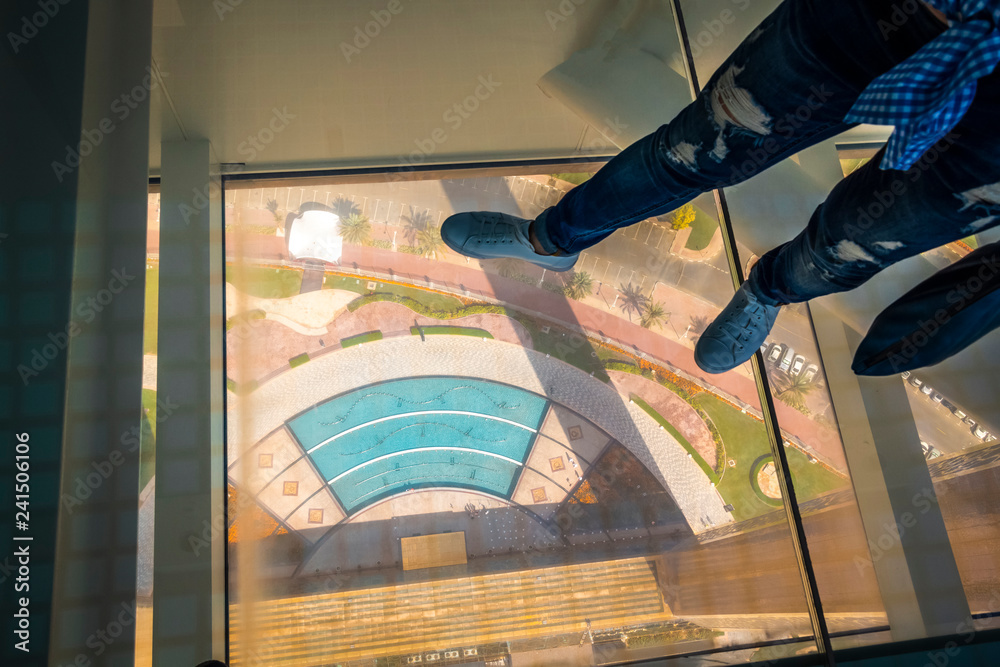 On a glass floor at high altitude in a Dubai Frame building.
