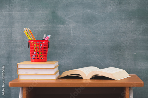 School books on desk, Back to school supplies. Books and blackboard on wooden background, education concept