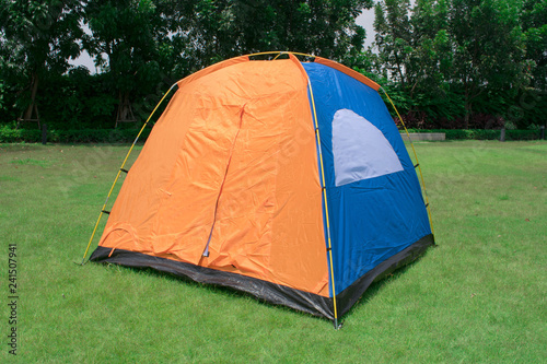 Orange and blue color family camping tent without rain fly setup on green park campsite.