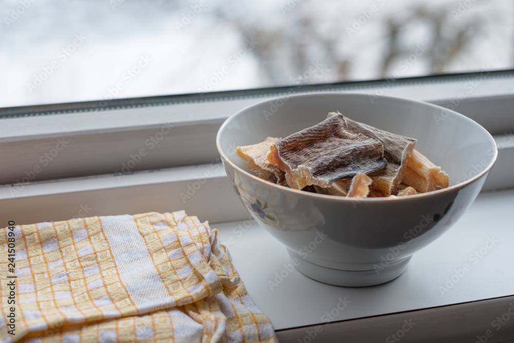 Skin cod fish drying fresh in ceramic bowl with table wipes on window sill  in winter foto de Stock | Adobe Stock