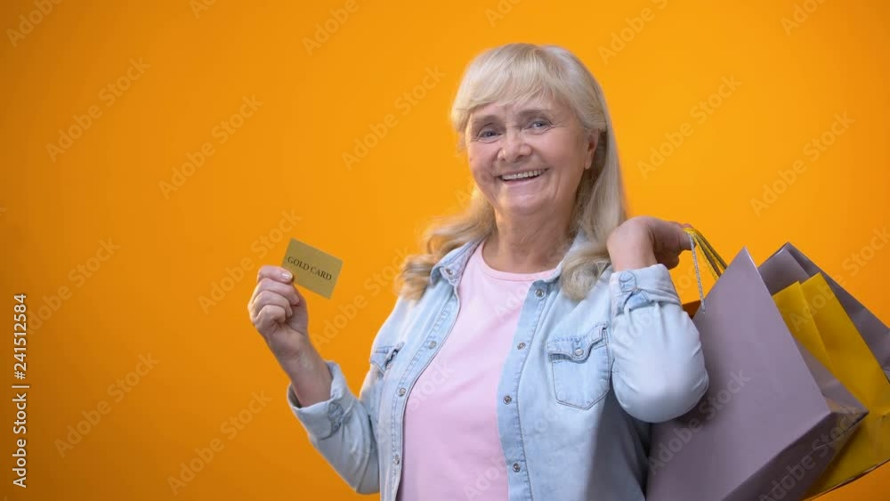 Joyful retiree lady showing shopping bags and golden card, standing customer Joyful retiree lady showing shopping bags and golden card, standing customer