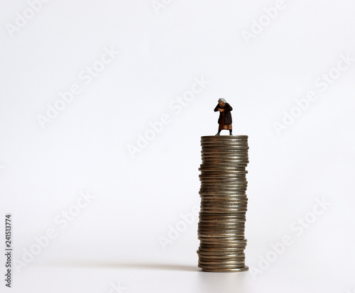 Miniature people with a pile of coins. The concept of old age and money.