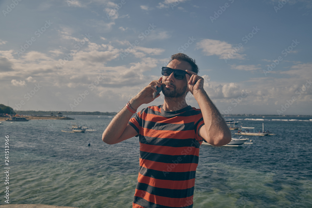Obraz premium Man using cellphone on the ocean beach.