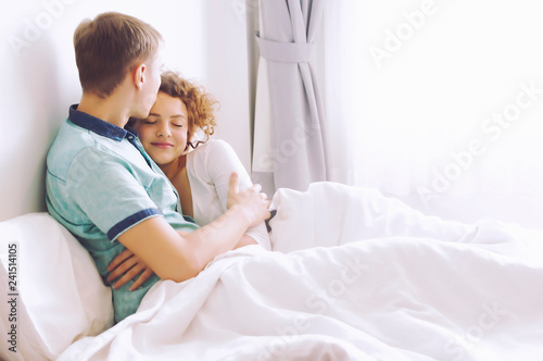 Young couple relaxing, embrace and have fun lying on the bed.