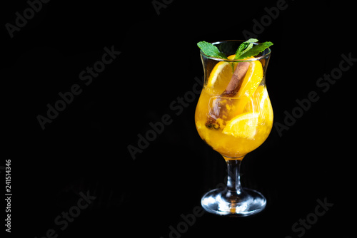Winter warming drink with pieces of orange and spices on a black background. Restaurant serving