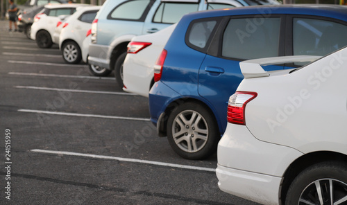 Closeup of rear or back side of white car with other cars parking in parking area in the evening. 