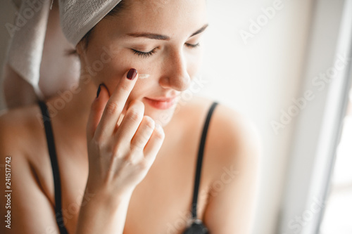 skin care. cute girl smears cheek face cream
