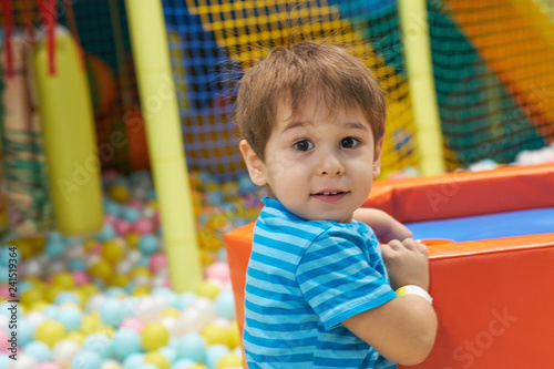 child of three years old is playing in a ball pool. boy smiling spends fun time in the children's room