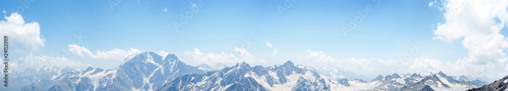 mountains peaks in the snow and clouds panoramic view