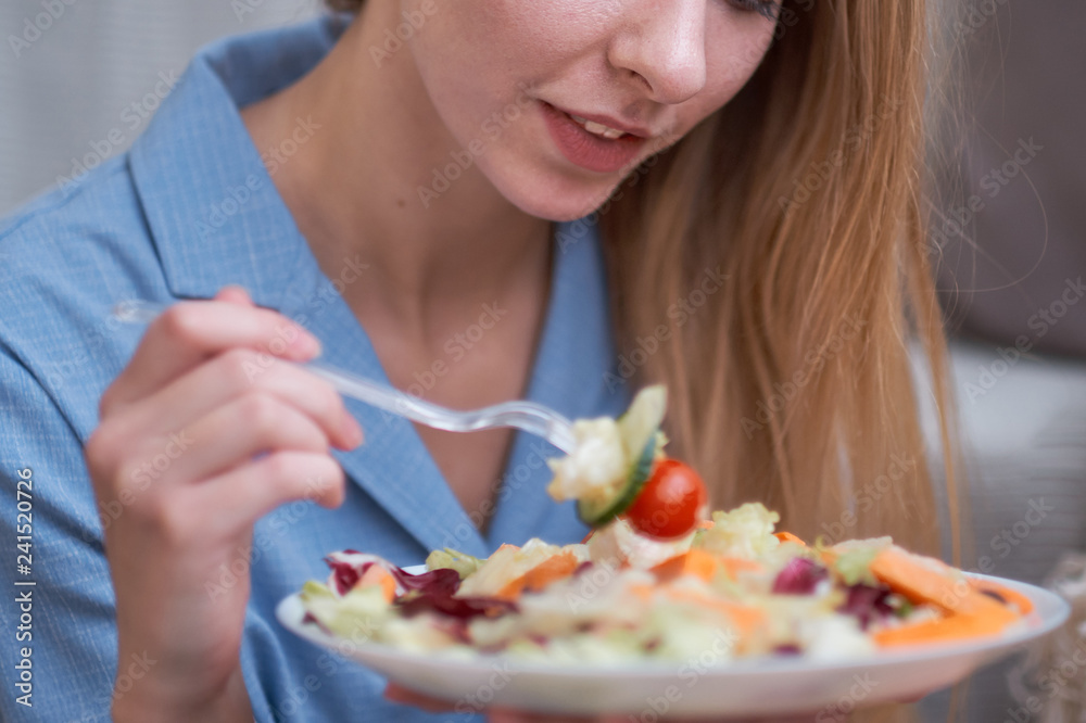 young woman is eating salad at home, diet concept. disgruntled person, depression from having to diet, lack of fat in the diet.