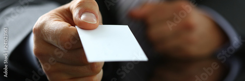 Male arm in suit give blank calling card to visitor closeup
