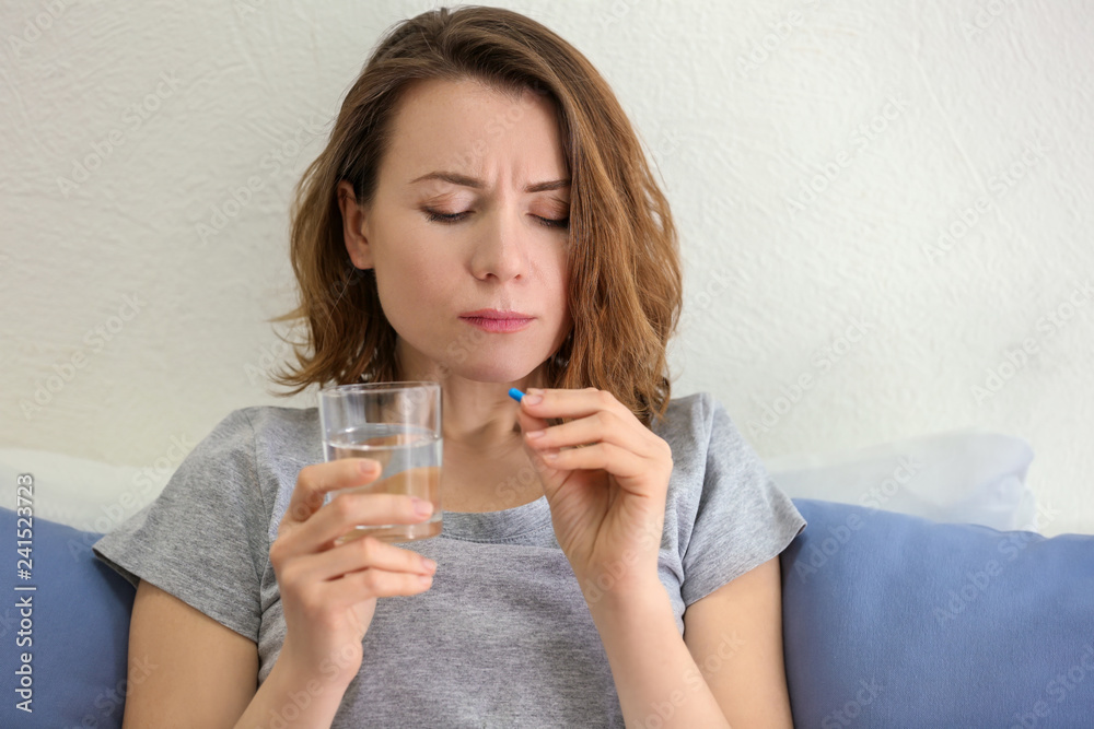 Young woman taking pill in bed Young woman taking pill in bed