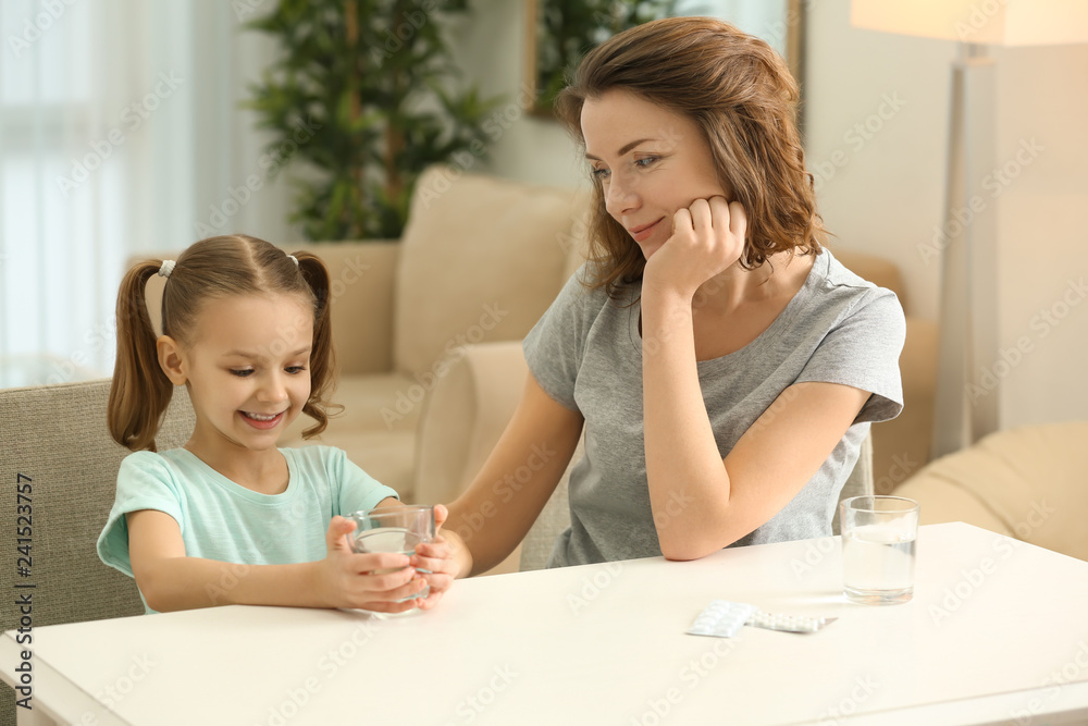 Young mother giving pill to her daughter at home Young mother giving pill to her daughter at home