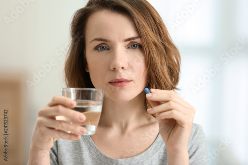 Young woman taking pill, indoors