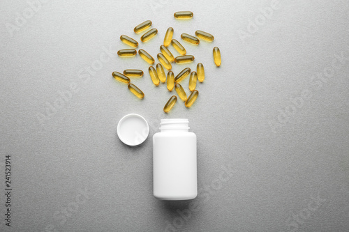 Container with pills on grey background