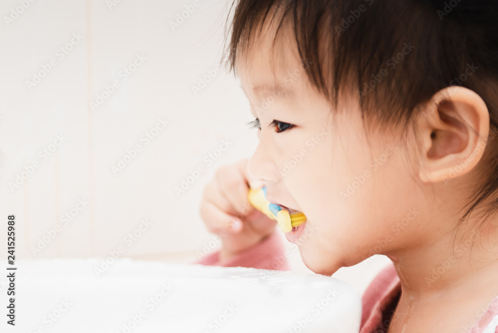 Sweet Asian child little girl brushing her teeth in bathroom Sweet Asian child little girl brushing her teeth in bathroom