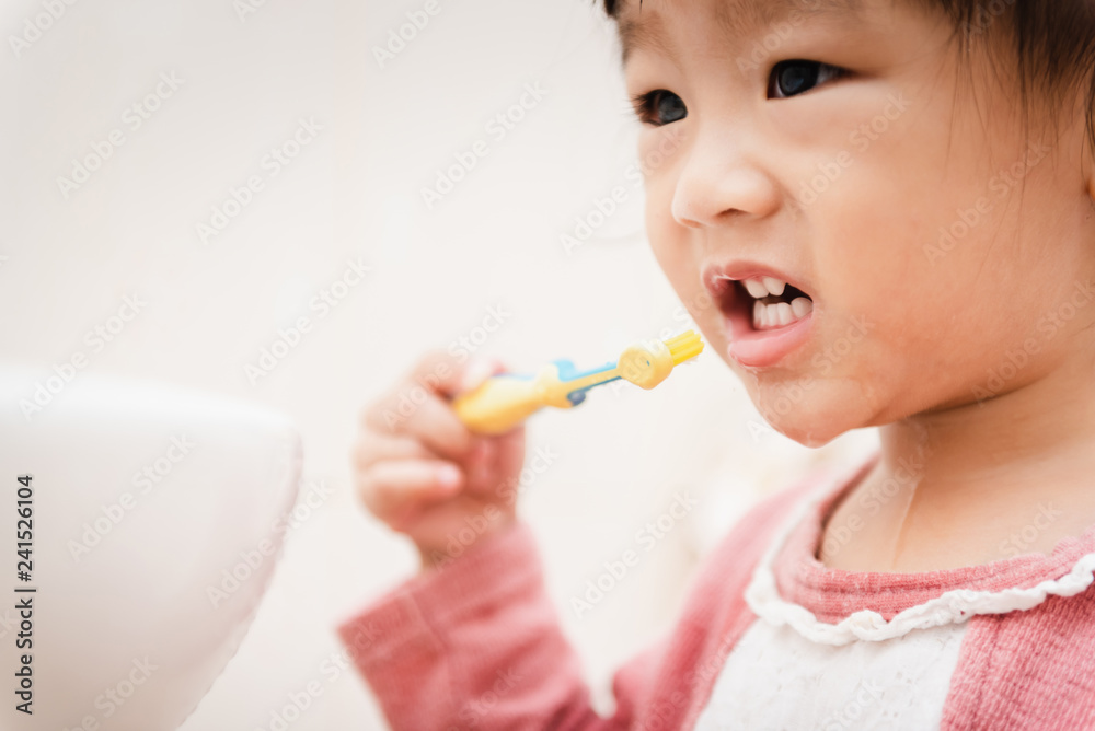 Sweet Asian child little girl brushing her teeth in bathroom Sweet Asian child little girl brushing her teeth in bathroom