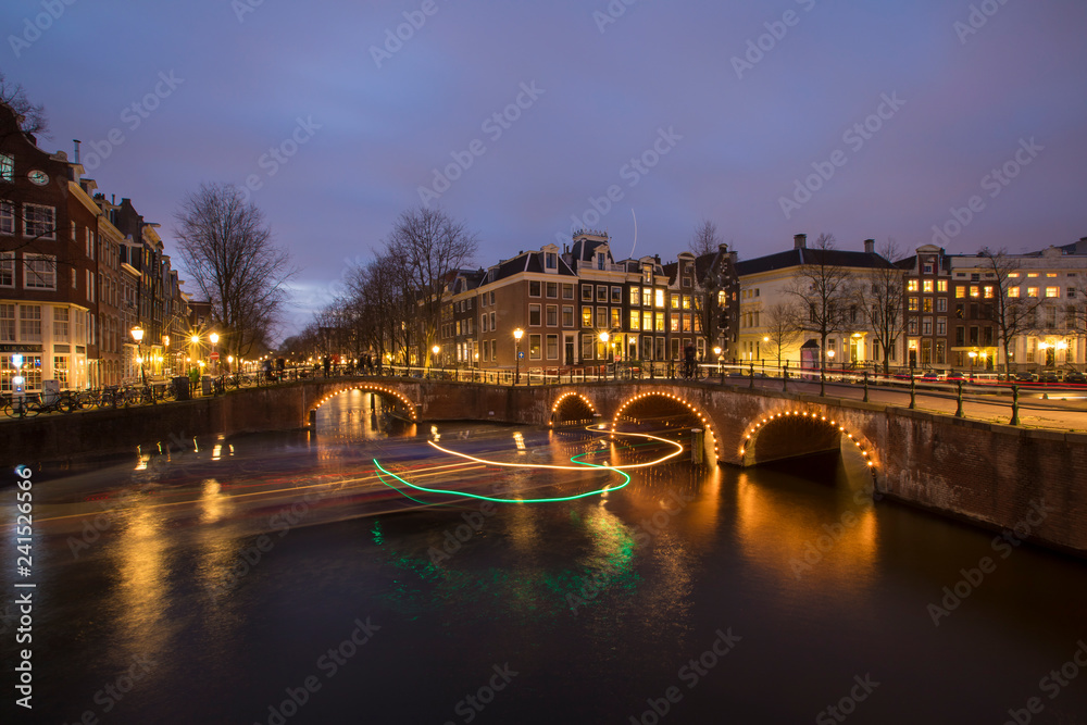 View on romantic canal Leidsegracht in Amsterdam at night with city lights, bridges and reflection on water