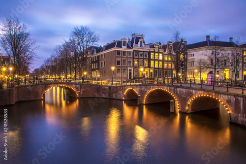 View on romantic canal Leidsegracht in Amsterdam at night with city lights, bridges and reflection on water
