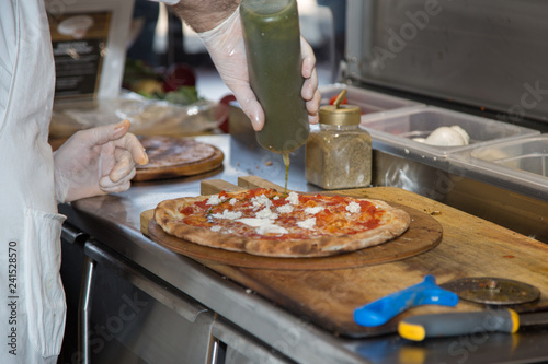 Pizza Maker who Prepares a Delicious Pizza with Cheese Mozzarella, Oil and Tomatoes