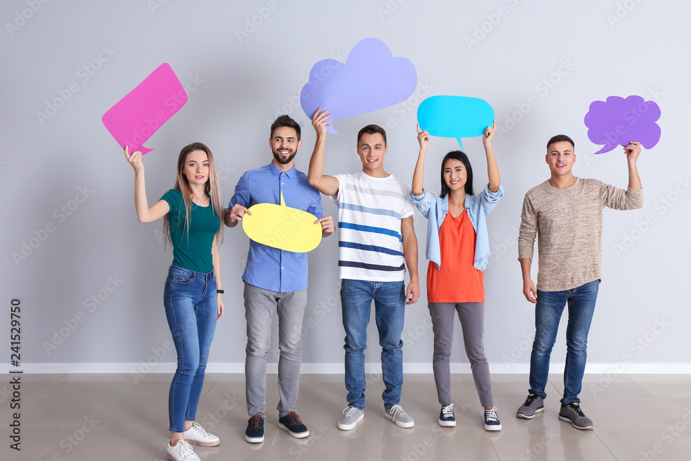 Naklejka premium Young people with blank speech bubbles near white wall