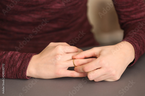 Woman trying to slip ring off her finger  closeup. Concept of divorce