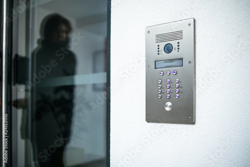 Woman silhouette preparing to enter modern luxury home with focus on the door digital interphone photo