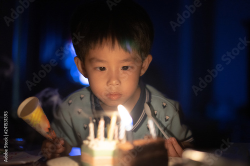 A happy kid is blowing candles on his birthday cake at his birthday party night.