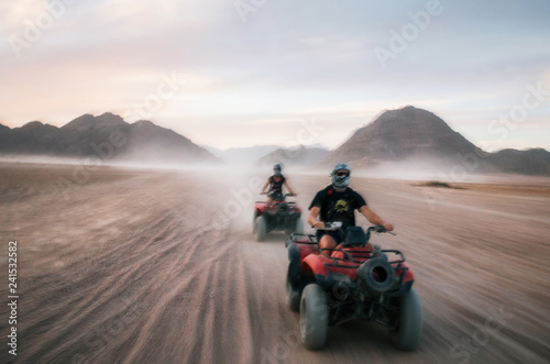 Buggy and ATV quads races in Sinai desert at sunset. Egyptian landscape with off-road vehicles and dust dirt road. Sharm el Sheikh, Egypt. Defocused motion blur