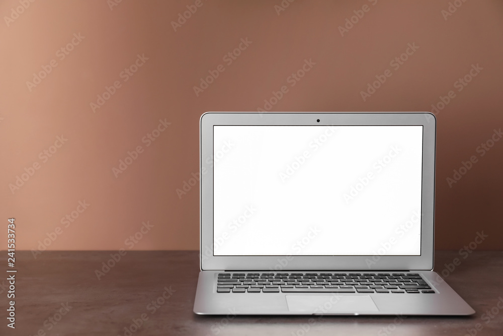 Modern laptop on table against color wall Modern laptop on table against color wall