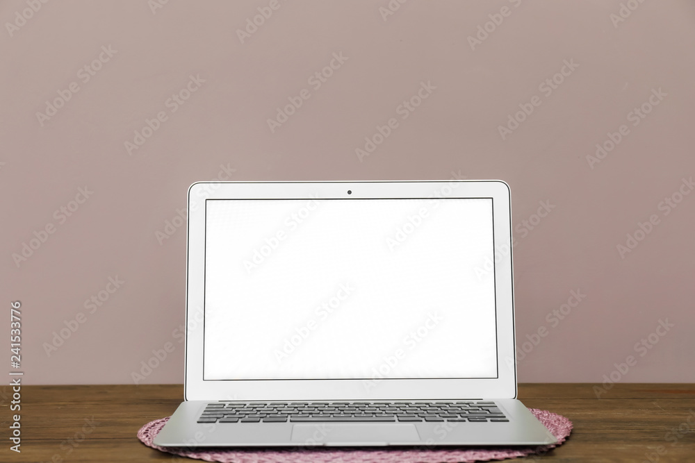 Modern laptop on table against color wall Modern laptop on table against color wall