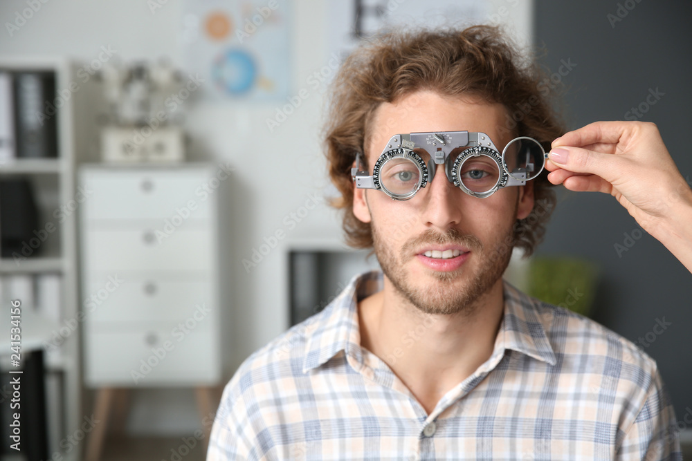 Young man with trial frames in ophthalmologist clinic Young man with trial frames in ophthalmologist clinic