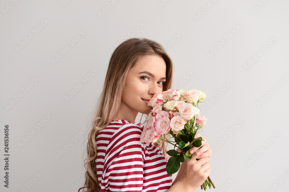 Beautiful young woman with bouquet of flowers on grey background