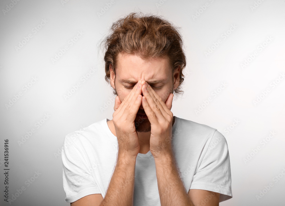 Young man suffering from headache on light background Young man suffering from headache on light background