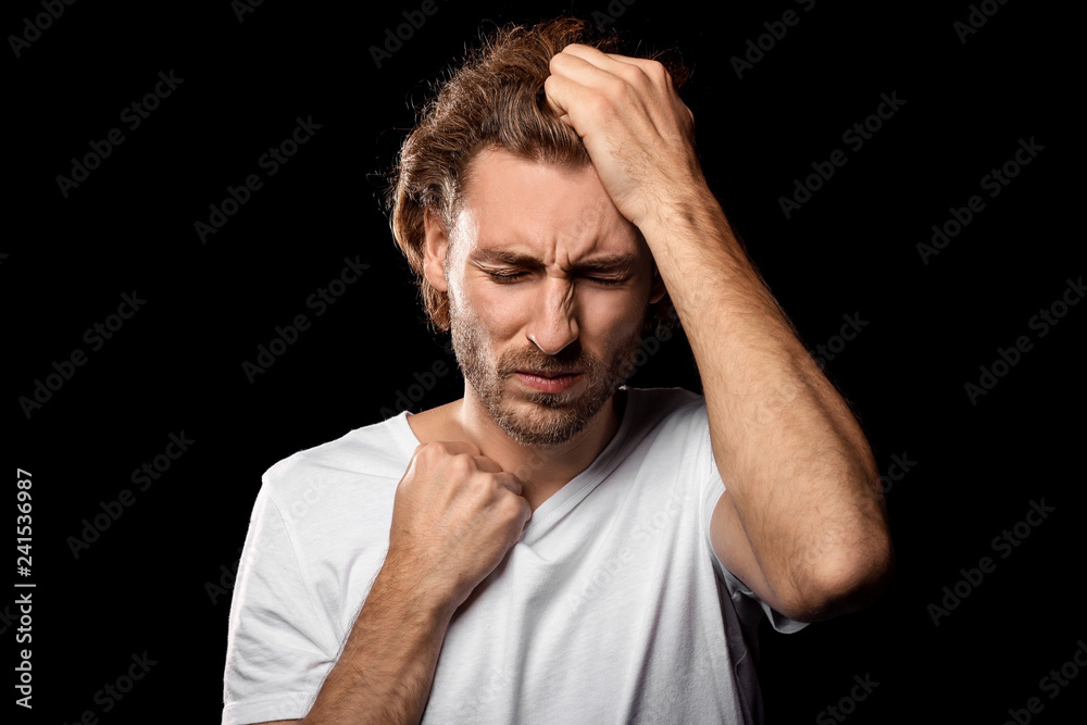Young man suffering from headache on dark background Young man suffering from headache on dark background